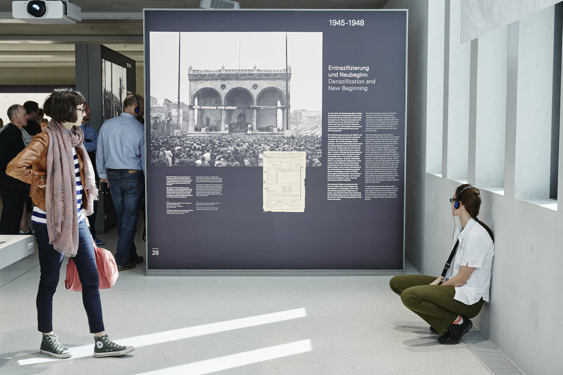 Two people standing in front of an exhibition panel dealing with the subject of de-Nazification.