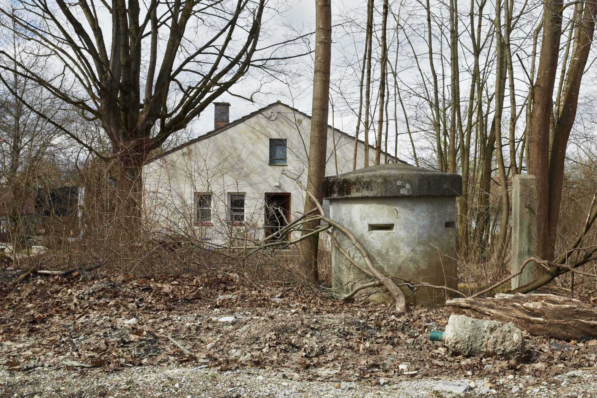 A barrack and a one-person bunker among trees in autumn.