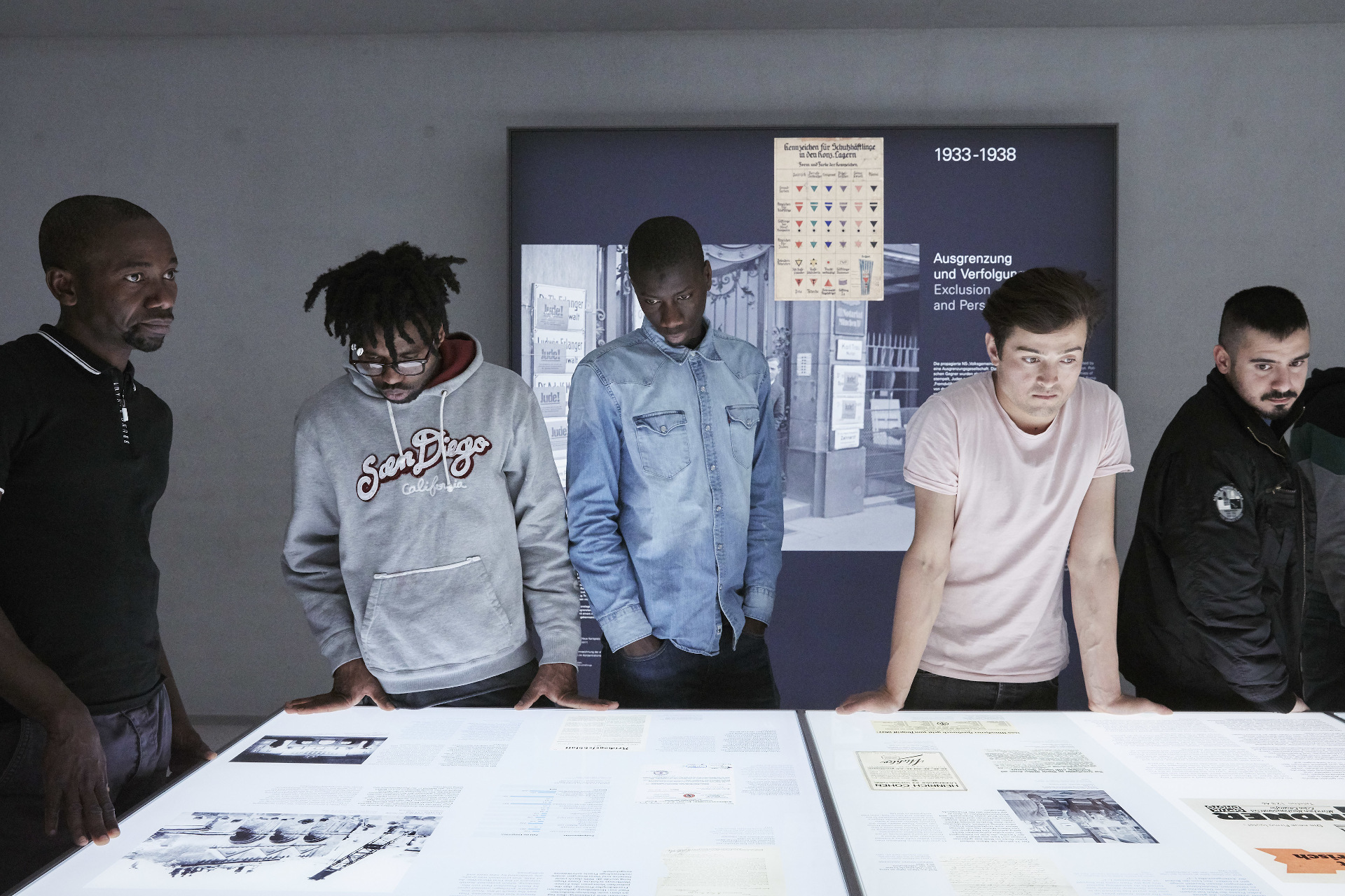 Five young people standing in front of one of the exhibition’s illuminated tables.