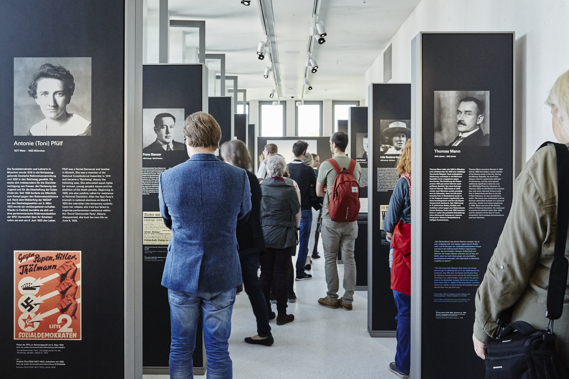 Several people looking at exhibition panels arranged on the left and right.