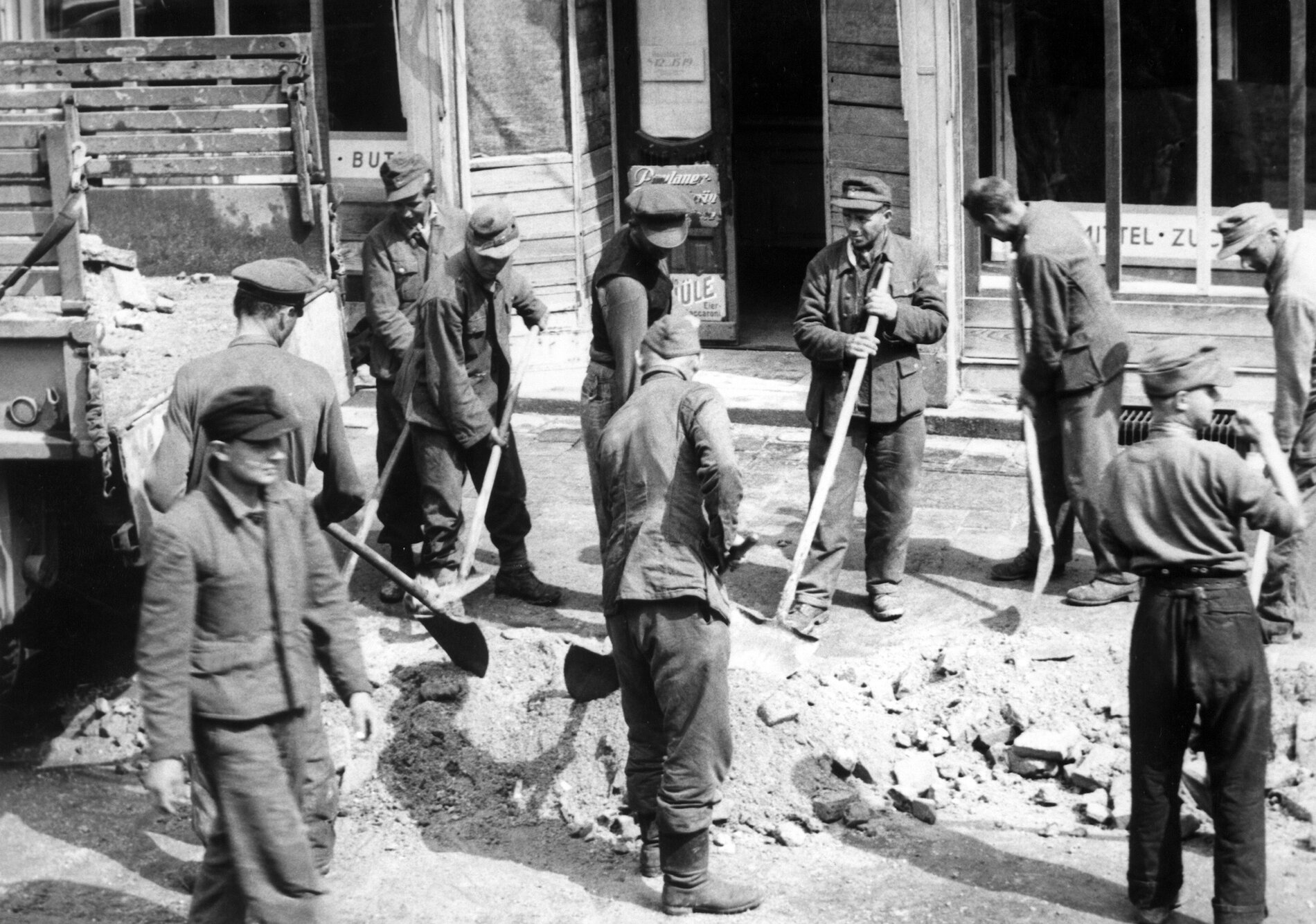 Archive photos of prisoners of war digging up streetcar tracks with shovels. 