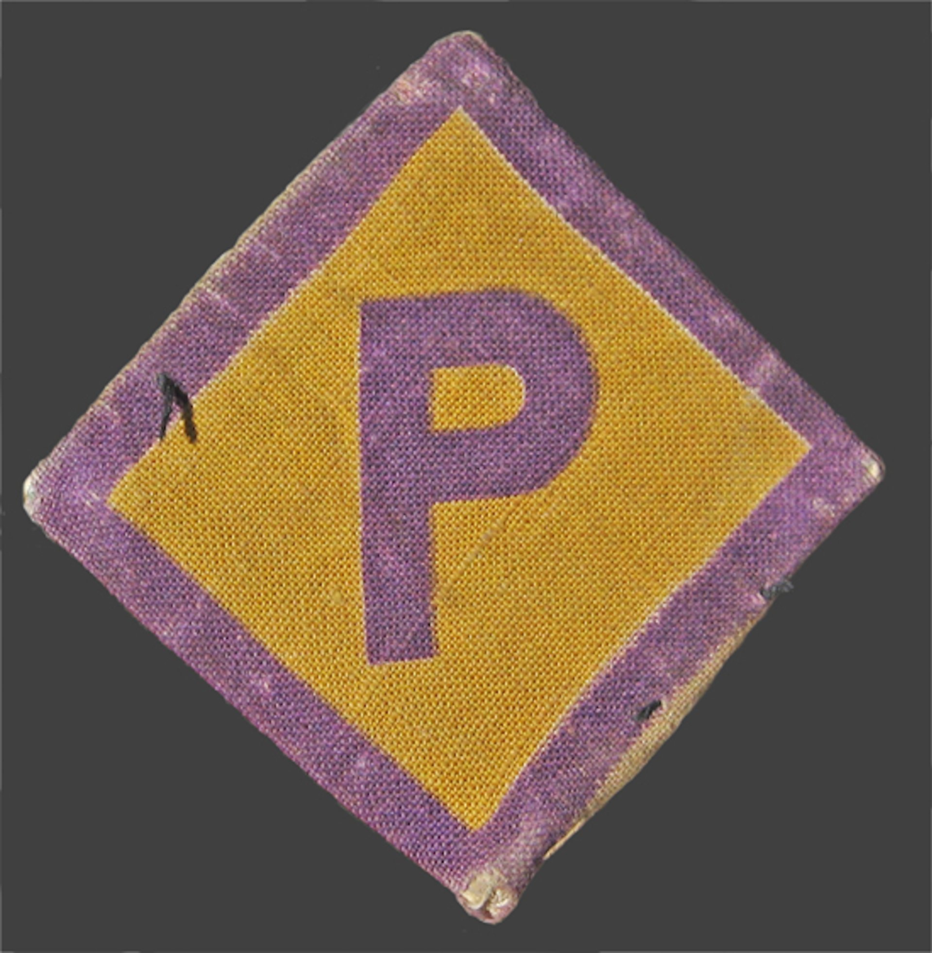 Ein viereckiger Aufnäher in der Farbe gelb mit lila Rändern und einem hervorgehobenem ‚P‘.