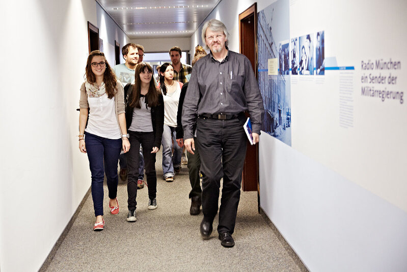 Several school students walking down a corridor at Bayerischer Rundfunk with their teacher.